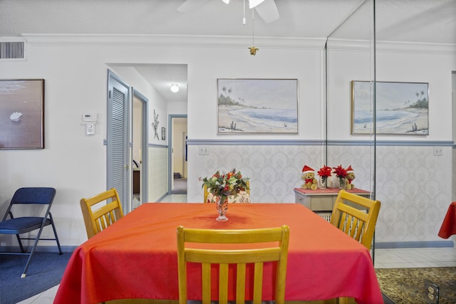 tiled dining room with ceiling fan and ornamental molding