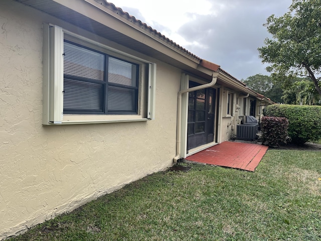 view of side of home with a lawn and central air condition unit