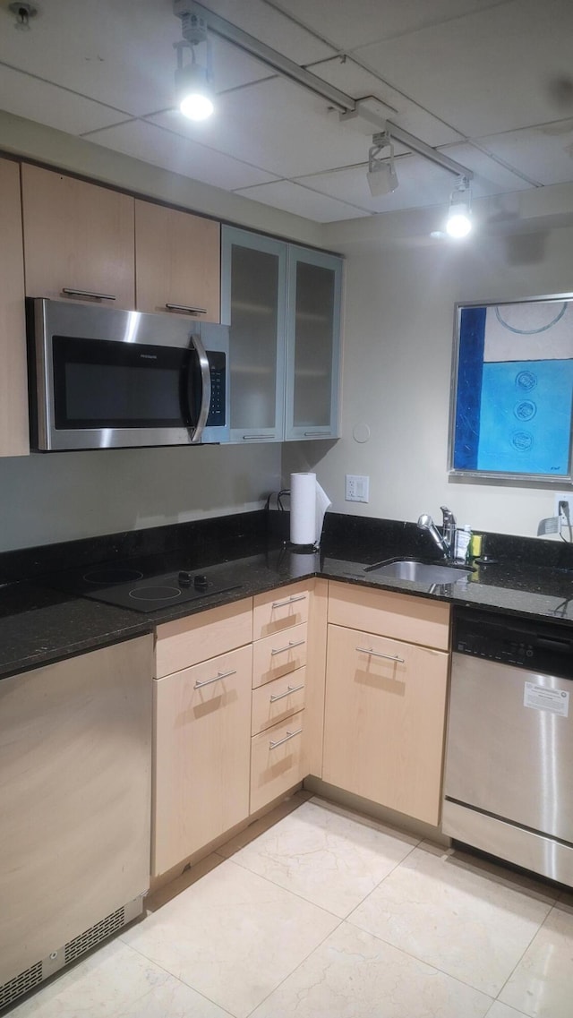 kitchen with light brown cabinetry, sink, dark stone counters, and appliances with stainless steel finishes