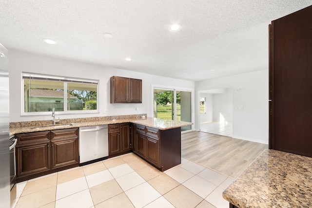 kitchen with kitchen peninsula, a textured ceiling, sink, light tile patterned floors, and dishwasher