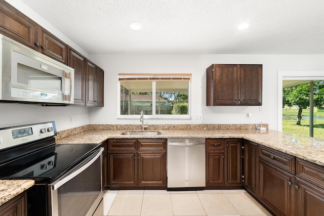 kitchen with a textured ceiling, stainless steel appliances, a wealth of natural light, and sink