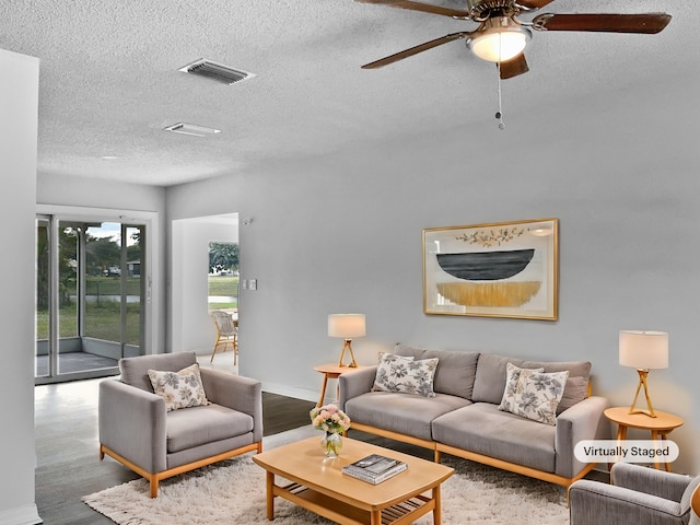 living room featuring hardwood / wood-style floors, ceiling fan, and a textured ceiling