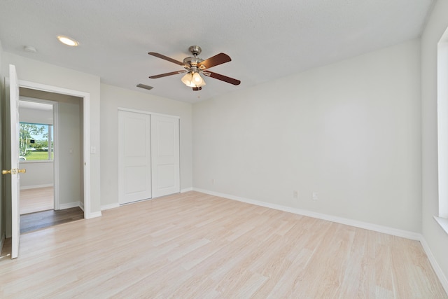 unfurnished bedroom featuring ceiling fan, light hardwood / wood-style floors, a textured ceiling, and a closet