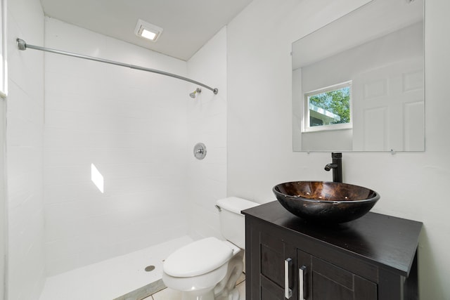 bathroom with a tile shower, vanity, and toilet