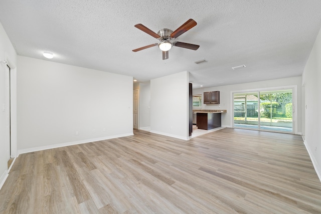 unfurnished living room with ceiling fan, light hardwood / wood-style floors, and a textured ceiling