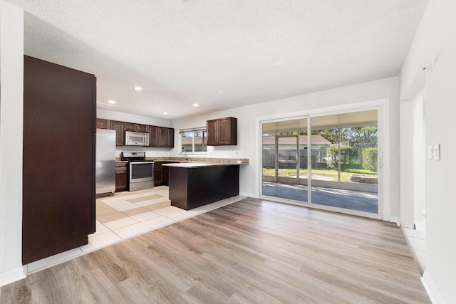 kitchen featuring sink, light hardwood / wood-style flooring, a textured ceiling, dark brown cabinets, and stainless steel appliances