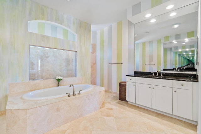 bathroom featuring tiled tub and vanity