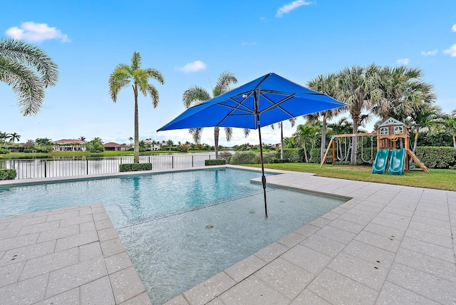 view of pool featuring a playground, a patio, and a water view