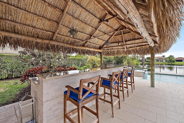 view of patio featuring an outdoor kitchen, a water view, a gazebo, a bar, and ceiling fan