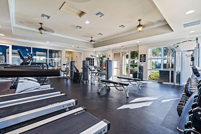 gym featuring a raised ceiling, crown molding, and ceiling fan