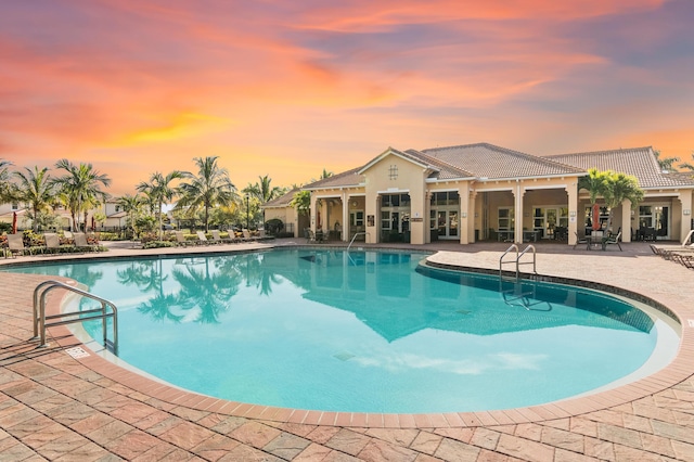 pool at dusk featuring a patio