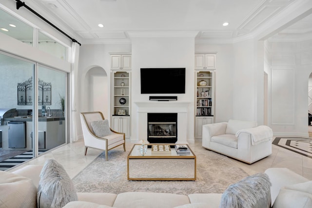 living room with built in shelves, sink, and ornamental molding