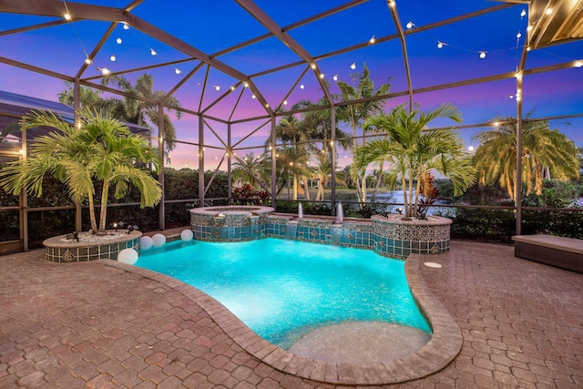 pool at dusk featuring a lanai, an in ground hot tub, pool water feature, and a patio