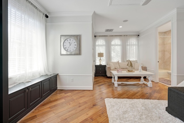 living area with light hardwood / wood-style floors and ornamental molding