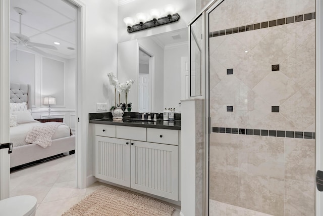 bathroom with ceiling fan, tile patterned flooring, a shower with door, vanity, and ornamental molding