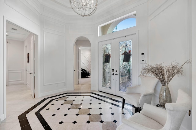 entryway with a chandelier, french doors, and light tile patterned floors