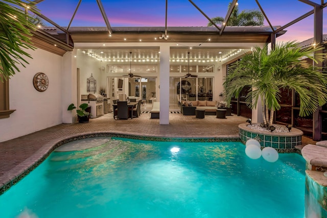 pool at dusk with glass enclosure, an outdoor living space, ceiling fan, and a patio