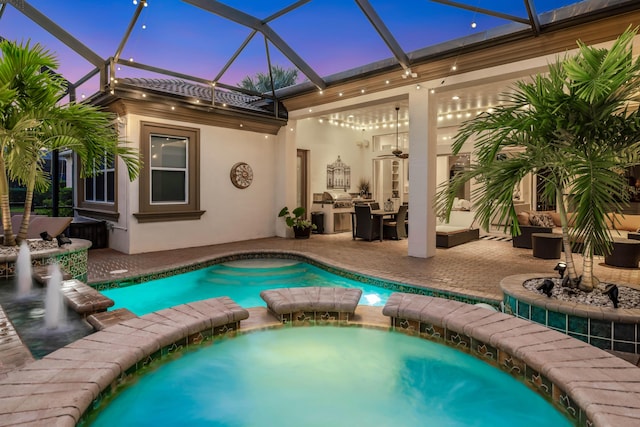 pool at dusk with a lanai, a patio area, and an in ground hot tub