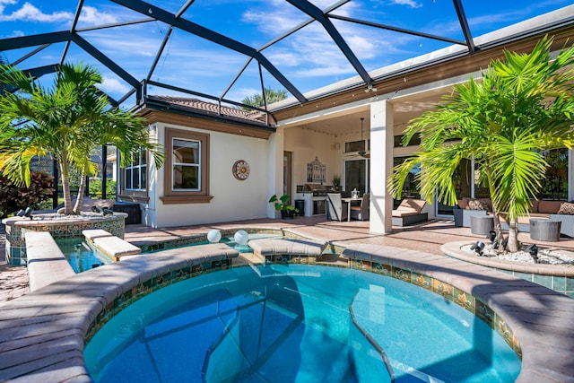 view of swimming pool featuring an outdoor kitchen, glass enclosure, a hot tub, and ceiling fan