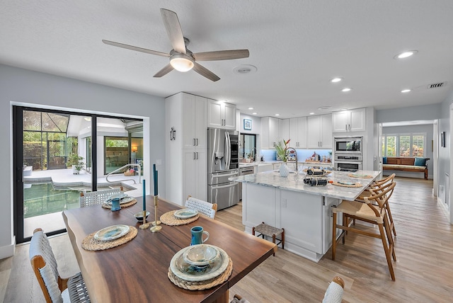 dining area featuring light hardwood / wood-style floors, ceiling fan, and sink