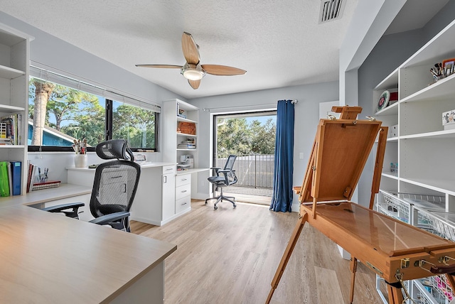 office with a textured ceiling, light hardwood / wood-style flooring, and ceiling fan