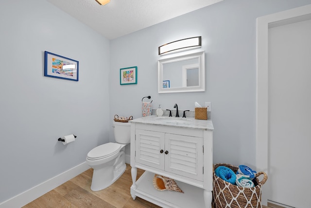 bathroom with hardwood / wood-style flooring, vanity, toilet, and a textured ceiling