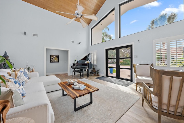 living room featuring ceiling fan, light wood-type flooring, and a towering ceiling