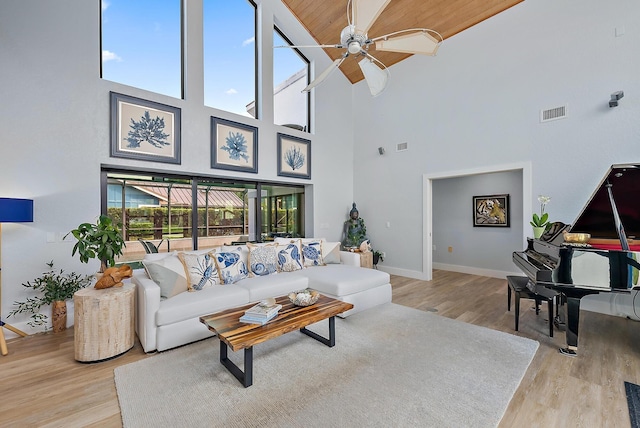 living room with a high ceiling, light wood-type flooring, ceiling fan, and wood ceiling