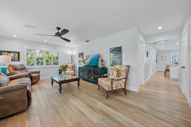 living room featuring a textured ceiling, light hardwood / wood-style flooring, and ceiling fan