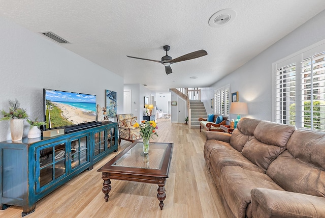 living room with ceiling fan, light hardwood / wood-style flooring, and a textured ceiling