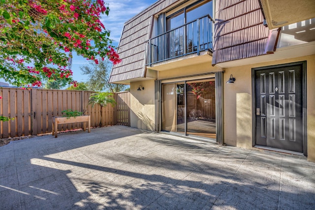 view of exterior entry with a balcony and a patio