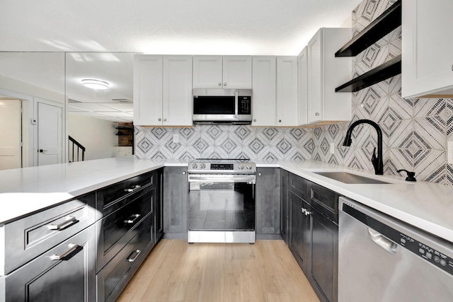 kitchen featuring sink, decorative backsplash, light hardwood / wood-style floors, kitchen peninsula, and stainless steel appliances