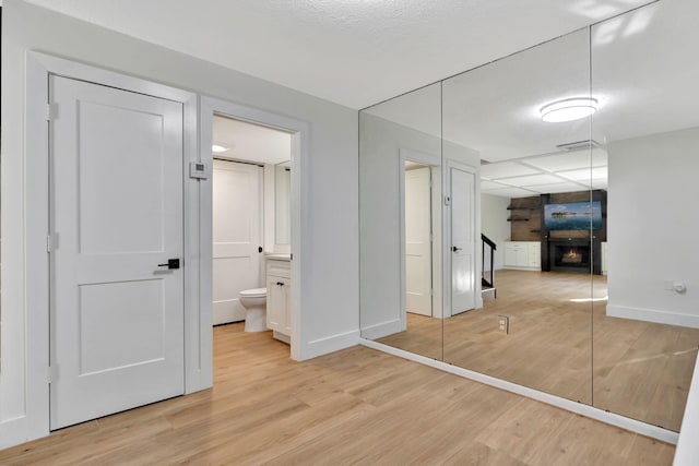 unfurnished bedroom featuring ensuite bathroom, a closet, and light wood-type flooring