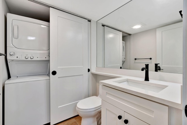 bathroom featuring vanity, stacked washer / drying machine, and toilet