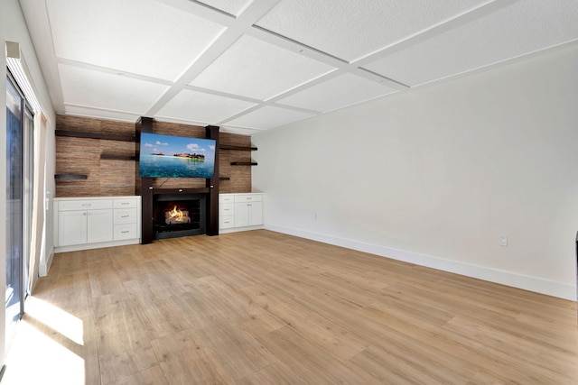 unfurnished living room with a fireplace, coffered ceiling, and light wood-type flooring