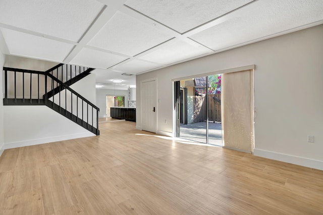 unfurnished living room with light hardwood / wood-style flooring and coffered ceiling