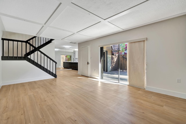 unfurnished living room with light hardwood / wood-style floors and coffered ceiling