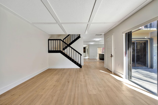 interior space featuring light wood-type flooring, a textured ceiling, and coffered ceiling