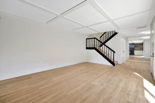 unfurnished living room with light hardwood / wood-style floors, a textured ceiling, and coffered ceiling