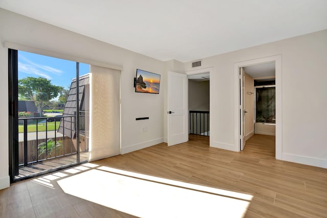 unfurnished bedroom with access to outside, ensuite bathroom, and light hardwood / wood-style flooring