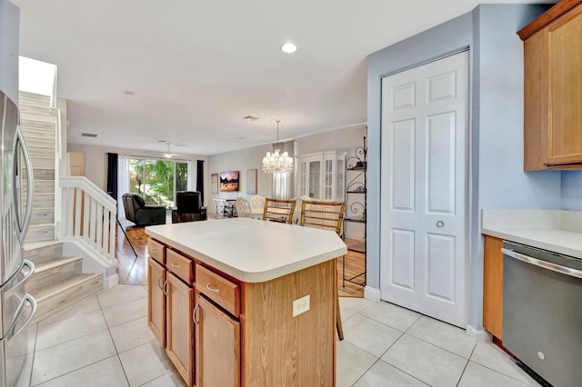 kitchen with a kitchen island, decorative light fixtures, light tile patterned floors, and appliances with stainless steel finishes