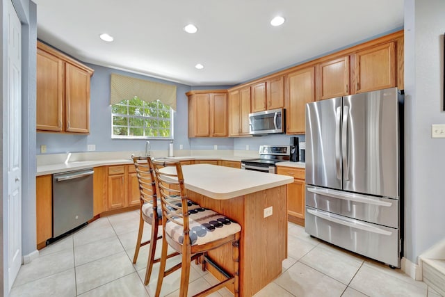 kitchen with light countertops, a center island, light tile patterned floors, and appliances with stainless steel finishes