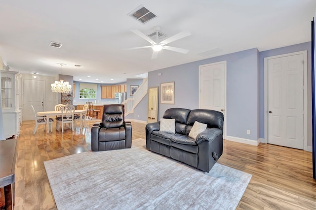 living room featuring ceiling fan with notable chandelier and light hardwood / wood-style floors