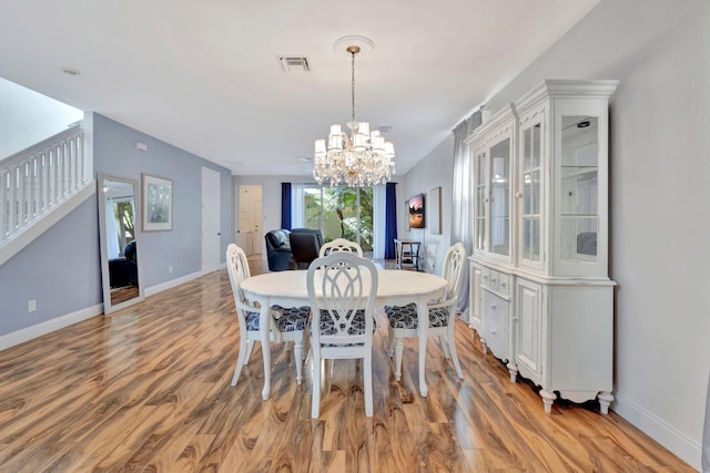 dining area featuring visible vents, baseboards, stairs, light wood-style floors, and a notable chandelier