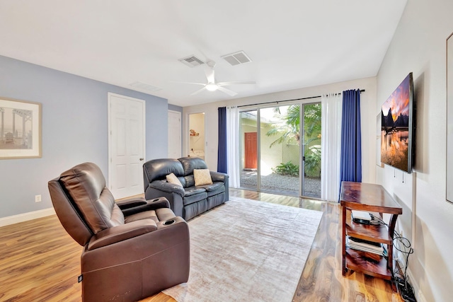 living area featuring baseboards, visible vents, light wood-style floors, and a ceiling fan