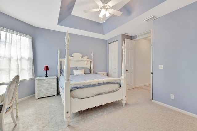 carpeted bedroom featuring a closet, a raised ceiling, and ceiling fan