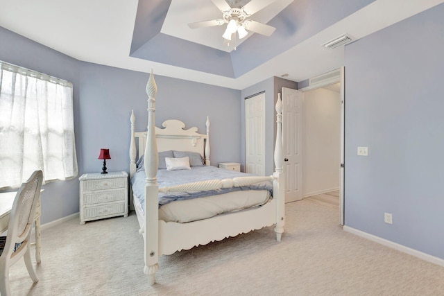 carpeted bedroom featuring baseboards, visible vents, a closet, and a raised ceiling