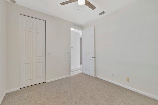 unfurnished bedroom with light carpet, a closet, and ceiling fan