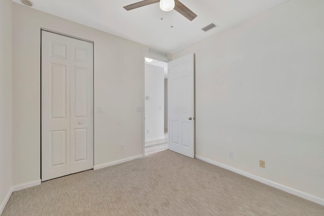 unfurnished bedroom featuring baseboards, visible vents, a ceiling fan, and light colored carpet
