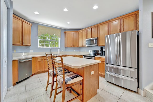 kitchen with a breakfast bar, a center island, light tile patterned floors, and stainless steel appliances